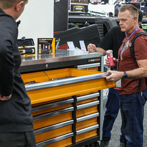 Two men looking at display of large rolling tool chest.