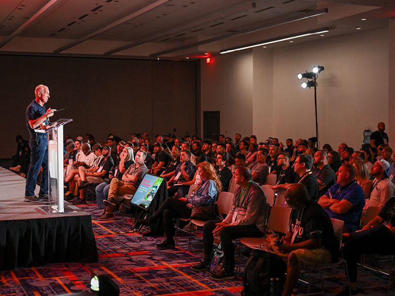 Speaker on stage under stage lighting at SEMA Education